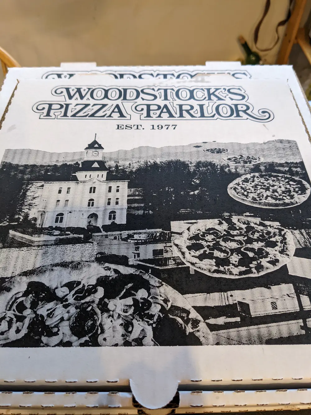 A Woodstock's Pizza Parlor box, Est. 1977, with pizzas flying over the Benton County Courthouse